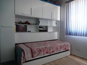 una camera da letto con armadi bianchi e una panca con mensola per libri di Apartamento na Praia a Ilhéus