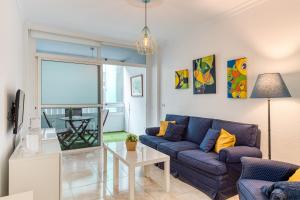 a living room with a blue couch and a table at Apartamento Canteras in Las Palmas de Gran Canaria