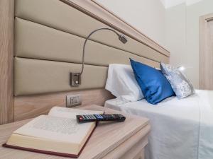 ein Schlafzimmer mit 2 Betten und einem Buch und einer Lampe in der Unterkunft L'Ambasciata Hotel de Charme in Cagliari