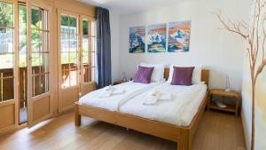 ヴェンゲンにあるLes Residences Waldbortのベッドルーム1室(白いシーツと紫色の枕が備わるベッド1台付)
