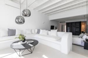 a white living room with a white couch and a table at Nimbus Mykonos in Agios Stefanos