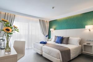 una habitación de hotel con una cama y un jarrón de flores en Aparthotel Esquinzo Y Monte Del Mar, en Playa de Jandía