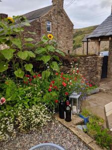 a garden with flowers and a stone wall at Fell View, Slaggyford in Brampton