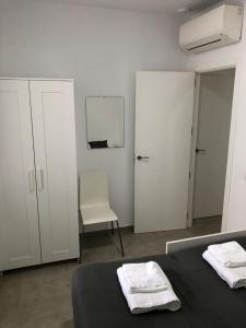 1 dormitorio blanco con 1 cama y 1 silla en Apartamento Gran Teatro Falla-La Caleta, en Cádiz