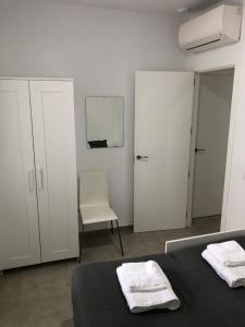 a white bedroom with a bed and a chair at Apartamento Gran Teatro Falla-La Caleta in Cádiz