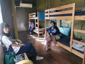 3 personas sentadas en una habitación con literas en Pickbaan, en Lamphun