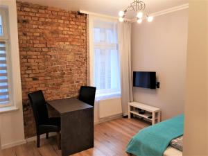 a bedroom with a brick wall and a desk and a bed at Apartament B&F Poznań Business & Family in Poznań