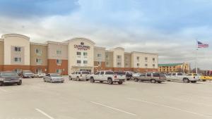 Candlewood Suites Gonzales - Baton Rouge Area, an IHG Hotel في غونزاليس: مبنى كبير به سيارات تقف في موقف للسيارات