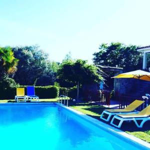 a swimming pool with two lawn chairs and umbrellas at Quinta da Chouza Agroturismo e Enoturismo in Celorico de Basto