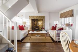 una sala de estar con muebles blancos y almohadas rojas. en Carr Cottage en Leeds