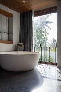 eine Badewanne im Bad mit einem großen Fenster in der Unterkunft Hotel Gahn - SHA Plus in Khao Lak