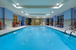 Holiday Inn Express Tower Center New Brunswick, an IHG Hotel في إيست برونزويك: مسبح كبير مع ماء أزرق في غرفة الفندق