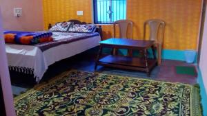 een slaapkamer met een bed en een tafel en stoelen bij Vamoose Mangrove Pitta in Kendrāparha