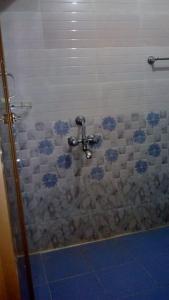 een badkamer met een douche met blauwe bloemen aan de muur bij Vamoose Mangrove Pitta in Kendrāparha
