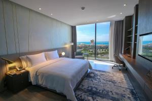 a bedroom with a large bed and a large window at Views Hotel & Residences in King Abdullah Economic City