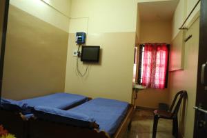 ein Krankenhauszimmer mit 2 Betten und einem TV in der Unterkunft R. VE. R Residency in Thanjavur