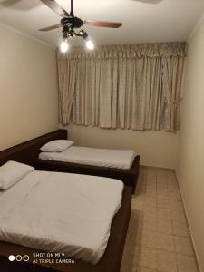 um quarto com 2 camas e uma ventoinha de tecto em Casa Gomes na Praia Grande