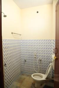 ein Bad mit einem WC und einer blau gefliesten Wand in der Unterkunft R. VE. R Residency in Thanjavur
