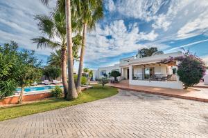 ein Haus mit einem Pool und Palmen in der Unterkunft Villa Can Petrus, con piscina y wifi gratis in Bucht von San Antonio