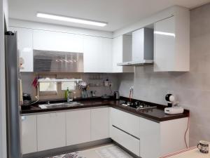 Una cocina con gabinetes blancos y encimeras negras. en Jeju The Heaven, en Jeju