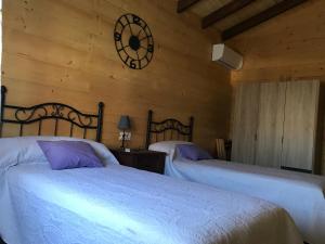 um quarto com duas camas e um relógio na parede em Casa rural Vega alta em Madridejos