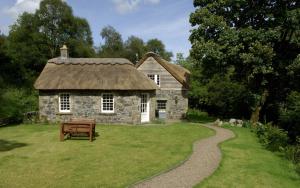 a stone house with a bench in front of it at Forget Me Not Holiday Cottage in Dalmellington