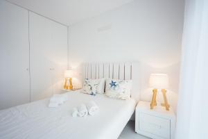 een witte slaapkamer met een wit bed met 2 lampen bij Janelas de Salir - By SCH in Salir de Porto +45 foto's