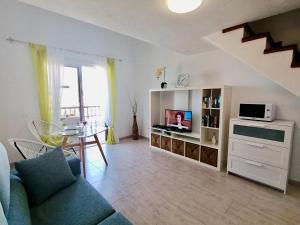 a living room with a couch and a tv and a table at Golden View Holiday Home in Playa de las Americas