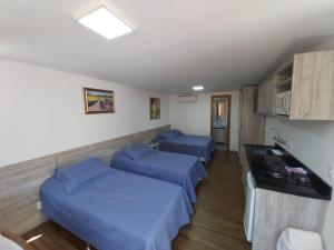 una camera ospedaliera con due letti e un bancone di 100% Flats a Gramado