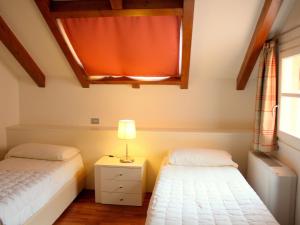 a bedroom with two beds and a lamp on a night stand at Brand new and elegant residence on Lake Maggiore in Meina