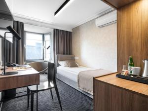 a hotel room with a bed and a desk at Hotel Logos Kraków in Krakow