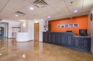 a lobby with a reception desk and an orange wall at Motel 6 Dallas – Irving DFW Airport South in Irving