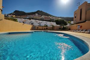 a large swimming pool with blue water in front of buildings at Cozy Townhouse With Ocean Views in Costa Adeje in Adeje
