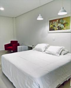 a bedroom with a white bed and a red chair at Hotel Picadão in São Pedro +45 photos