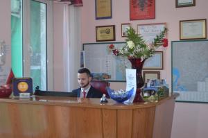 Un uomo è seduto alla reception di Hotel Kaduku a Shkodër