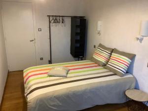 um quarto com uma cama com um cobertor listrado colorido em Belge ' Attitude Gîte 2 chambres em Commequiers