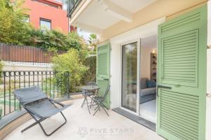 um pátio com portas verdes, uma mesa e cadeiras em Villa Artemys - Five Stars Holiday House em Saint-Jean-Cap-Ferrat