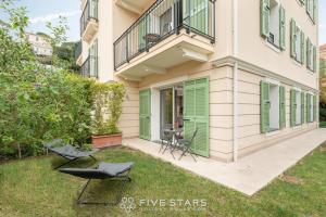 a house with green doors and chairs in the yard at Villa Artemys - Five Stars Holiday House in Saint-Jean-Cap-Ferrat