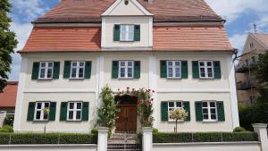 ein weißes Haus mit grünen Rollläden und einer Tür in der Unterkunft Hotel Falk in Krumbach