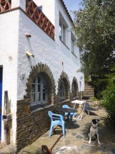 a dog sitting in front of a house with a table and chairs at Apartment Hibiscus Cadaqués in Cadaqués