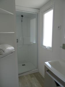 baño blanco con ducha y lavamanos en Camping Via Romana, en Prunelli-di-Fiumorbo