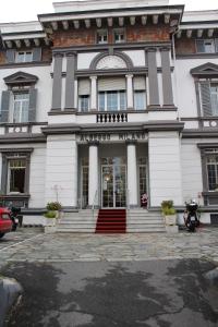 - un grand bâtiment blanc avec une porte d'entrée et des escaliers dans l'établissement Hotel Milano, à Sanremo