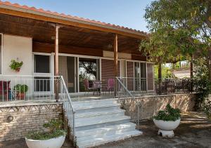 ein Haus mit einer Treppe und einer Veranda mit Stühlen in der Unterkunft Marathos beach House in Marathón