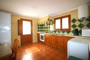 a kitchen with wooden cabinets and green and white tiles at Casa la Borna in Begur