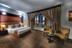 a bedroom with a bed and a chair and a window at Aryana Hotel in Sharjah