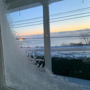 a snow covered street with a view of the water at Spouter Inn Bed & Breakfast in Lincolnville