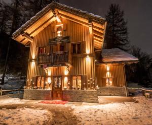 une maison en bois éclairée dans la neige dans l'établissement Chalet Plan Gorret, à Courmayeur