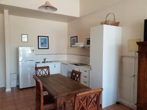 uma cozinha com uma mesa de madeira e um frigorífico branco em Granita's - 2 bedroom converted South Fremantle warehouse apartment em Fremantle