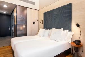 a bedroom with a large white bed and a lamp at One Shot Tabakalera House in Donostia-San Sebastián