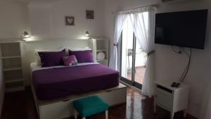 a bedroom with a purple bed and a television at Luminoso Depto con terraza propia y en la mejor ubicación in Córdoba